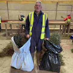 Ray Jenkins, owner of RJ Trees and Hedging, showing the bagging options available for forestry (white co-extruded bags) or farmers (black bags) and in the background a team of seasonal workers are grading (putting into sizes) the bare root tree saplings and hedging plants.